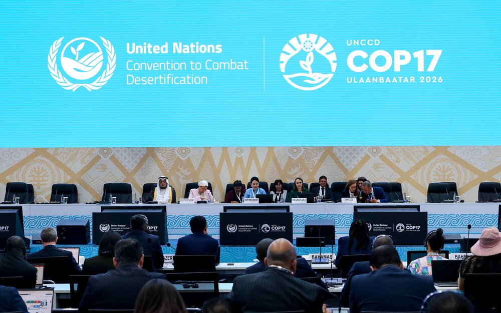 Podium der UN-Konferenz zur Bekämpfung der Wüstenbildung (UNCCD COP17) in Ulaanbaatar 2026 mit internationalen Delegierten vor einer großen, hellblauen Leinwand.